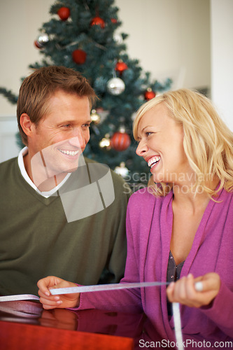 Image of Happy couple, festive season and ribbon for gift wrapping by christmas tree, love and care in house. Woman, man and smile for presents for together for giving, kindness and bonding in home on holiday