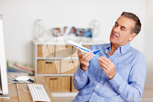 Image of Mature man, thinking and toy plane for travel, vacation and holiday planning with a smile at home. Happy, airplane model and retirement of a male person with confidence from trip and air traveling