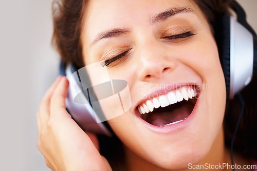 Image of Music, headphones and happy woman singing in house with freedom, good mood or vibes. Earphones, karaoke and face of person with eyes closed, smile or energy while listening to radio, audio or podcast