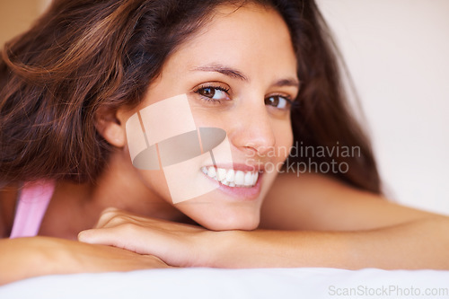 Image of Smile, portrait and face of young woman relaxing on bed on a weekend morning at modern home. Happy, beautiful and female person with positive, good and confident attitude in bedroom at house.