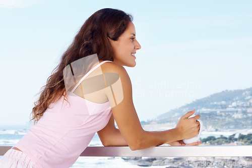 Image of Happy, balcony and woman with coffee by ocean for summer holiday, vacation and weekend. Travel, hotel resort and person with warm drink for adventure, relaxing and freedom with scenic view of nature