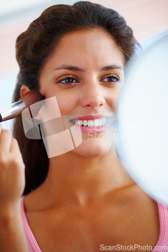 Image of Woman, face and makeup brush with smile for beauty, cosmetics and facial skincare with mirror in home. Person, happy and glow application with product and hand for wellness, cosmetology and aesthetic