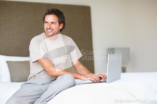 Image of Working, man in bed and laptop to work from home, thinking and sitting in pyjamas for freelance job. Technology, entrepreneur and remote worker for online, happiness and marketing projects