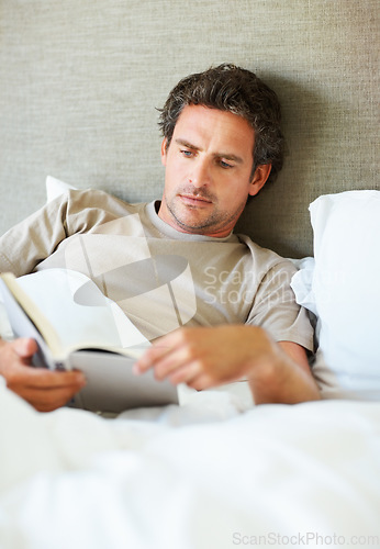 Image of Man, reading and relax in bed with book, storytelling or learning about self care, information or knowledge. Mature, person and research history in biography, novel or fiction in home or bedroom