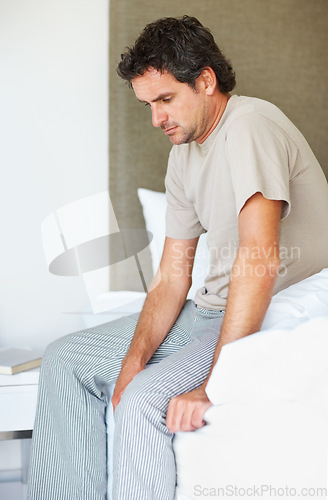 Image of Thinking, sad and man in bed in depression, anxiety or frustrated, lonely or mental health crisis in home. Tired, fatigue and person in bedroom stress, insomnia challenge and wake up in the morning