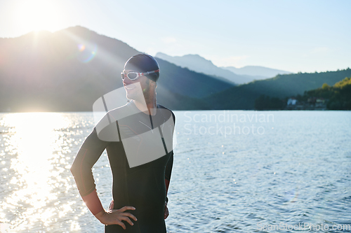 Image of Authentic triathlon athlete getting ready for swimming training on lake