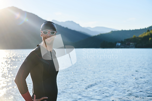 Image of Authentic triathlon athlete getting ready for swimming training on lake