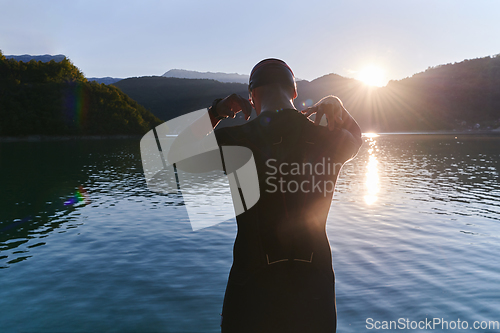 Image of Authentic triathlon athlete getting ready for swimming training on lake