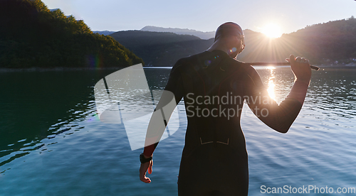 Image of Authentic triathlon athlete getting ready for swimming training on lake