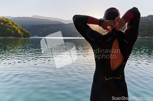 Image of Authentic triathlon athlete getting ready for swimming training on lake