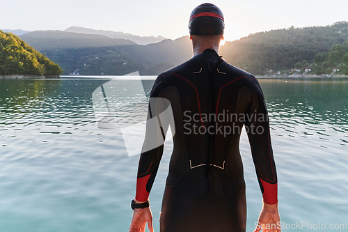 Image of Authentic triathlon athlete getting ready for swimming training on lake
