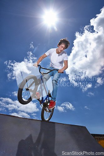 Image of Ride, bike and teenager on ramp for sport performance, jump or training for event at park with blue sky mockup. Bicycle, stunt or balance on edge of board in trick for cycling competition challenge