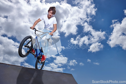 Image of Riding, bike and teen on ramp for sport performance, jump or training for event at park with blue sky mockup. Bicycle, stunt or kid balance on edge of board in trick for cycling competition challenge