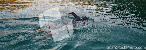 Image of A professional triathlete trains with unwavering dedication for an upcoming competition at a lake, emanating a sense of athleticism and profound commitment to excellence.