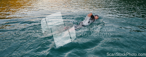 Image of A professional triathlete trains with unwavering dedication for an upcoming competition at a lake, emanating a sense of athleticism and profound commitment to excellence.