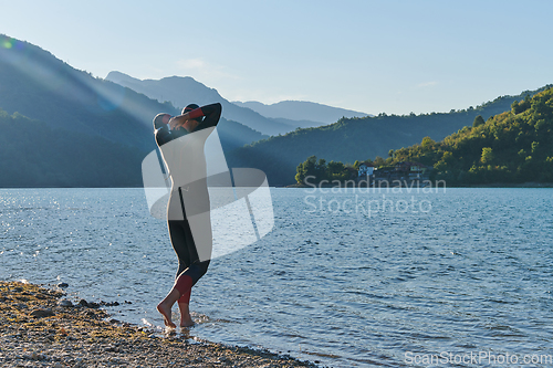 Image of Authentic triathlon athlete getting ready for swimming training on lake