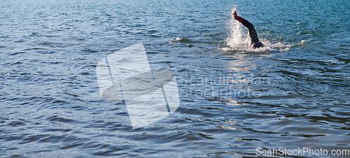 Image of Triathlon athlete swimming on lake in sunrise wearing wetsuit