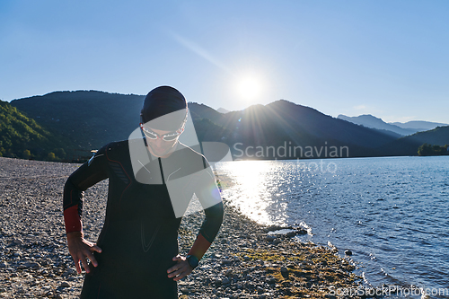 Image of Authentic triathlon athlete getting ready for swimming training on lake