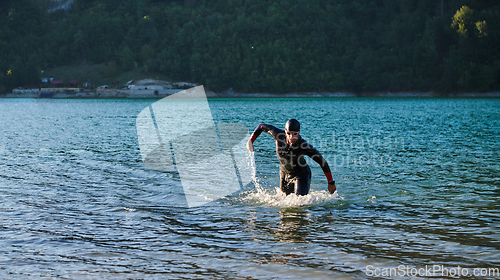 Image of Triathlon athlete starting swimming training on lake