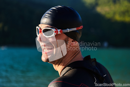 Image of Authentic triathlon athlete getting ready for swimming training on lake