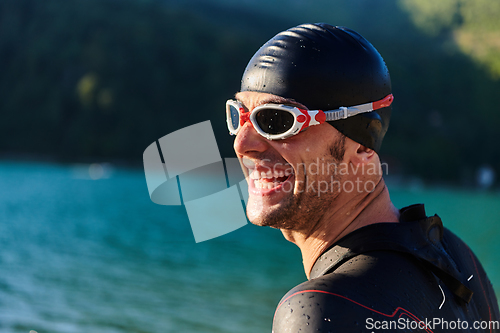 Image of Authentic triathlon athlete getting ready for swimming training on lake