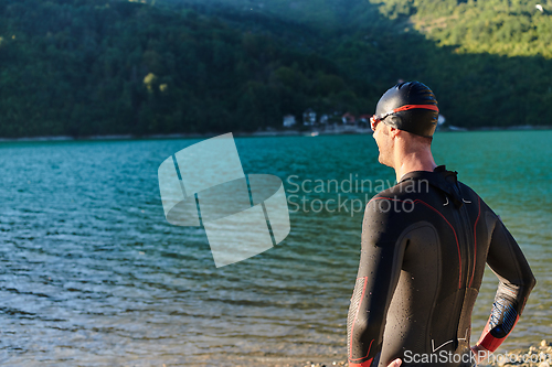 Image of Authentic triathlon athlete getting ready for swimming training on lake