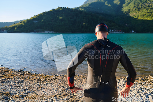 Image of Authentic triathlon athlete getting ready for swimming training on lake