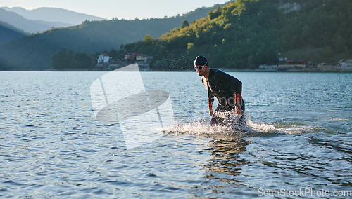 Image of Triathlon athlete starting swimming training on lake