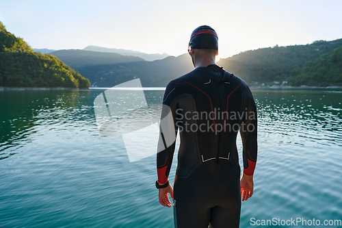 Image of Authentic triathlon athlete getting ready for swimming training on lake