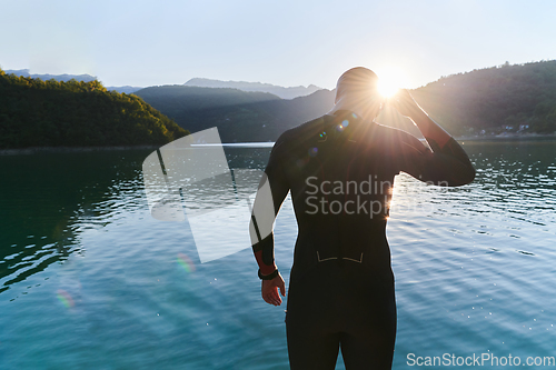 Image of Authentic triathlon athlete getting ready for swimming training on lake