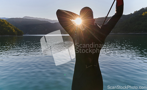 Image of Authentic triathlon athlete getting ready for swimming training on lake