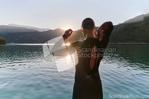 Image of Authentic triathlon athlete getting ready for swimming training on lake