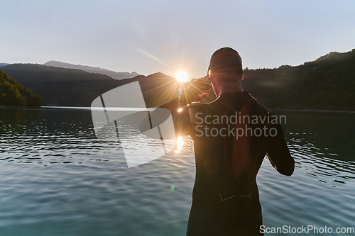 Image of Authentic triathlon athlete getting ready for swimming training on lake