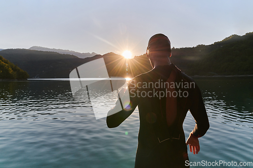 Image of Authentic triathlon athlete getting ready for swimming training on lake