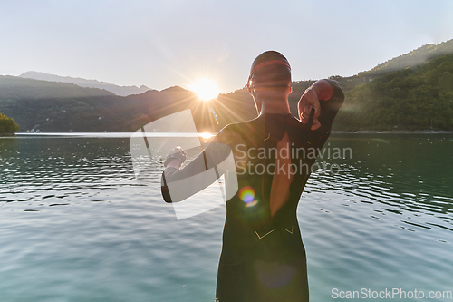 Image of Authentic triathlon athlete getting ready for swimming training on lake