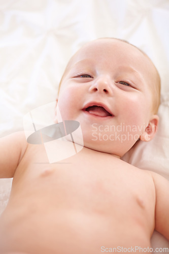 Image of Happy baby on bed, funny and top view portrait of young child in development, excited or relax at home. Face, above and infant kid laugh in nursery, rest in bedroom or healthy body, cute or adorable