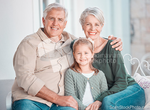 Image of Grandparents, girl and portrait on couch, smile or hug for care, bonding or love in home living room. Old man, elderly woman and kid with happy embrace on lounge sofa, relax and pride in family house
