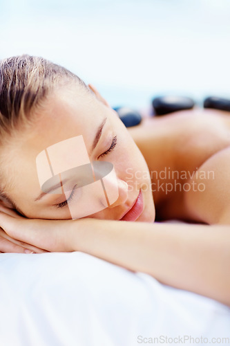 Image of Hot stone, massage and relax woman at a spa for wellness treatment and detox. Calm, muscle healing recovery and a female person with sleep at a resort or hotel with beauty therapist with skincare