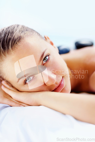 Image of Portrait, spa and woman with hot stone massage, relax or stress relief body treatment at a wellness resort. Luxury, zen and face of female person at a salon for healing, therapy or vacation pamper