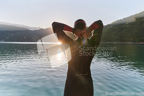 Image of Authentic triathlon athlete getting ready for swimming training on lake