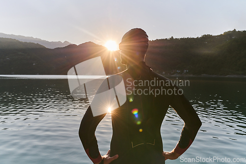 Image of Authentic triathlon athlete getting ready for swimming training on lake