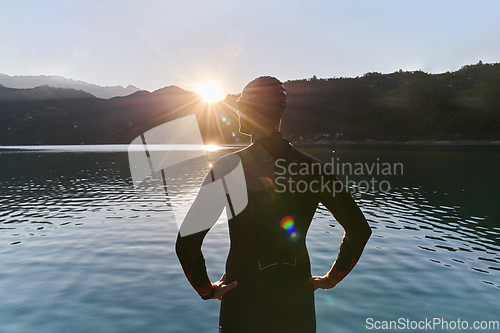 Image of Authentic triathlon athlete getting ready for swimming training on lake