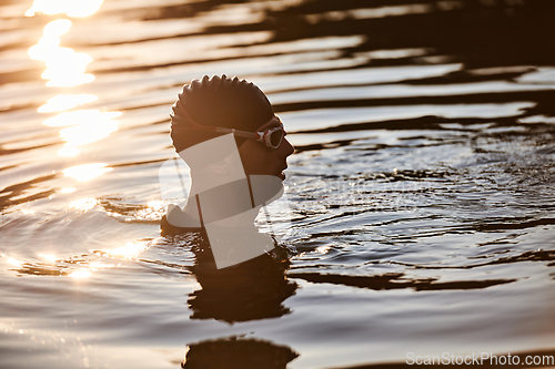 Image of A triathlete finds serene rejuvenation in a lake, basking in the tranquility of the water after an intense training session