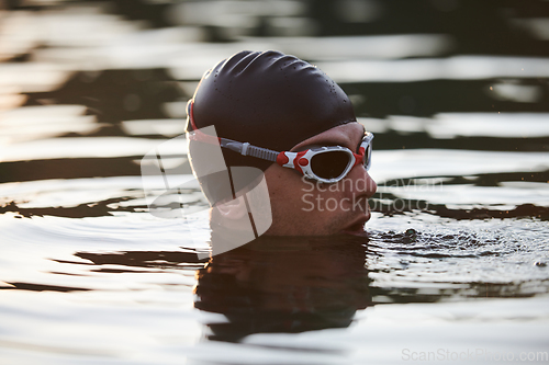 Image of A triathlete finds serene rejuvenation in a lake, basking in the tranquility of the water after an intense training session