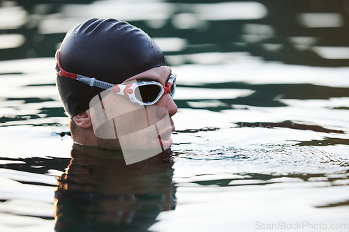 Image of A triathlete finds serene rejuvenation in a lake, basking in the tranquility of the water after an intense training session