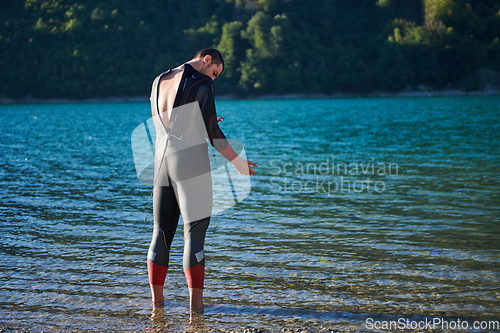 Image of Authentic triathlon athlete getting ready for swimming training on lake