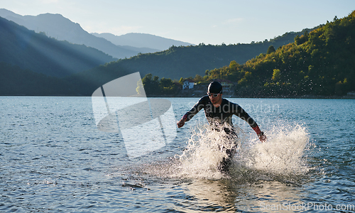 Image of Triathlon athlete starting swimming training on lake