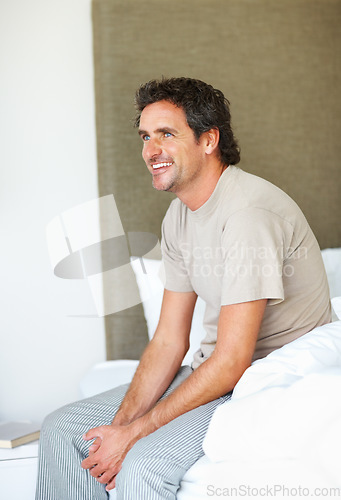 Image of Bedroom, thinking and man with a smile, morning and peace with happiness, calm and wellness. Person, home and guy with health, bed and wonder with thoughts, start the day and remember with apartment