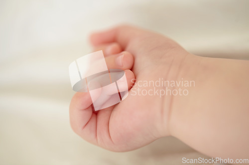 Image of Relax, development and the hand of a baby closeup in a nursery or bedroom of a home for rest at bedtime. Kids, sleeping or wellness with the fist and fingers of a newborn infant child lying on a bed