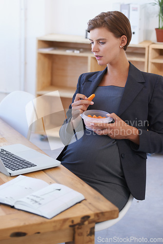 Image of Business woman, pregnant and eating carrots for healthy diet, nutrition or food at office. Female person or employee in pregnancy or maternity with laptop and natural organic vegetables at workplace